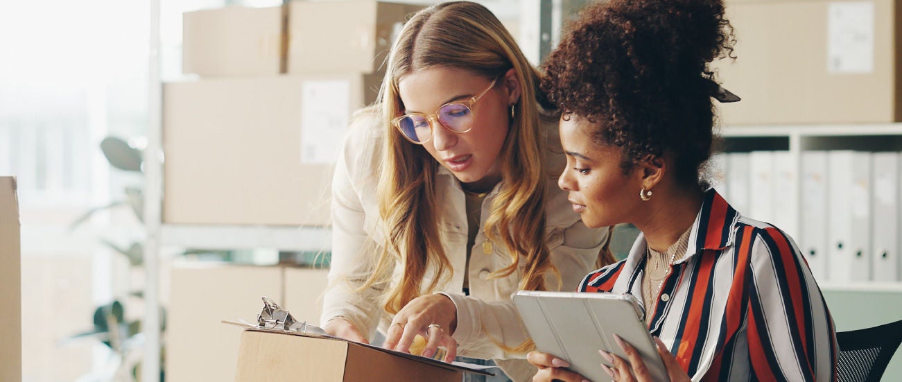 Businesswomen looking at a clipboard and discussing.