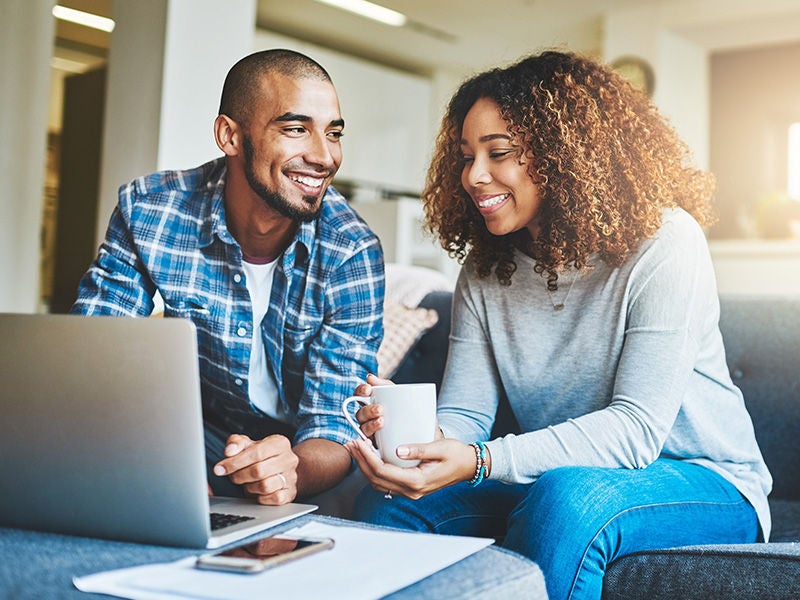 A man and a woman enjoying coffee in front of their laptop. 