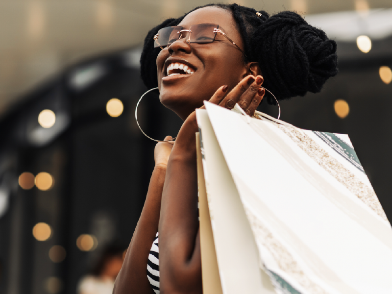 A woman carrying shopping bags and smiling.