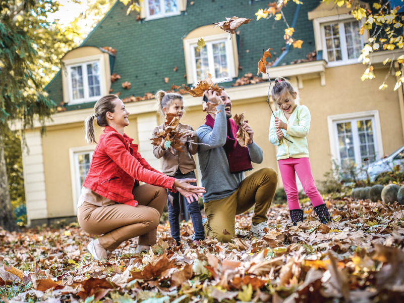 a family playing in the leaves during fall
