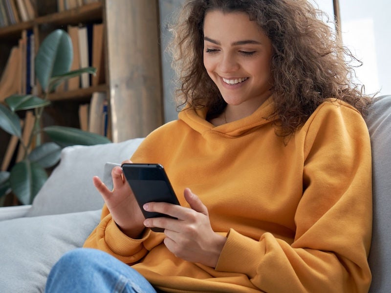 An image of a teenage girl on her phone smiling. 