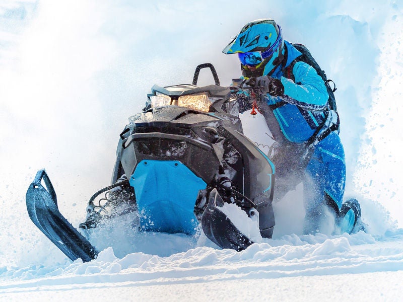 a man riding a snowmobile through deep powder.
