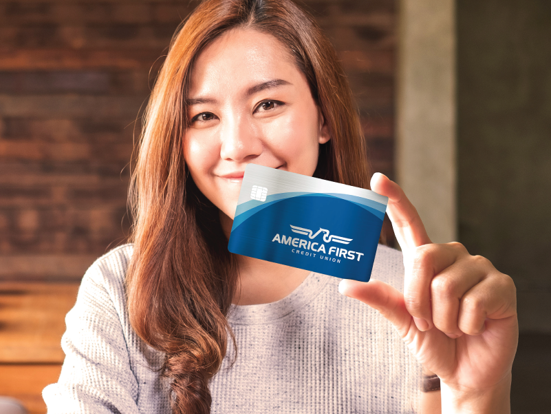 A woman holding an America First Visa and smiling.