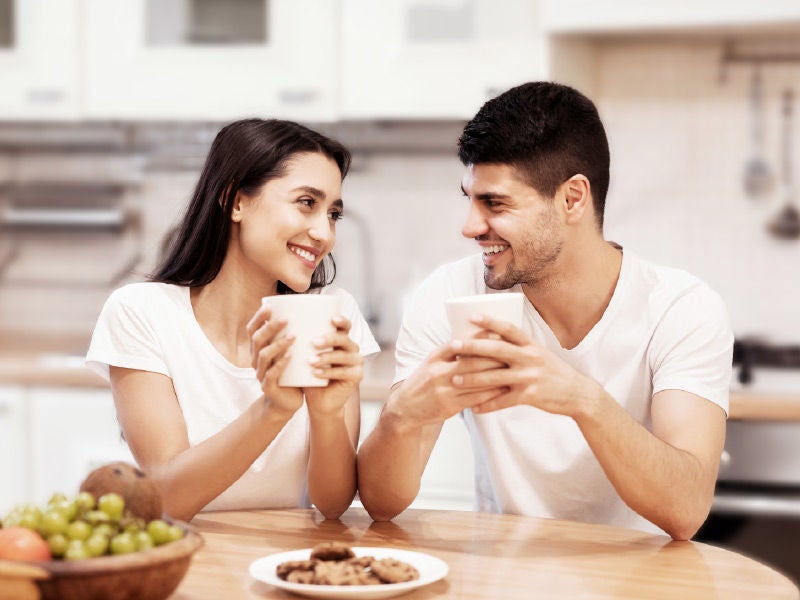 A man and woman drinking coffee at a table.
