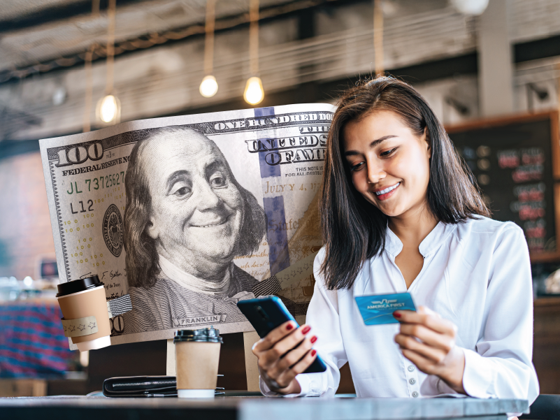 An image of a woman looking at her phone and holding her America First visa.