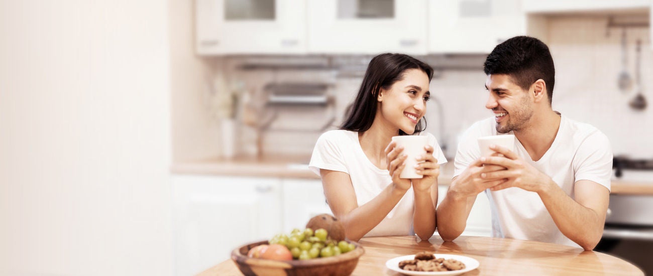 A man and woman drinking coffee at a table.