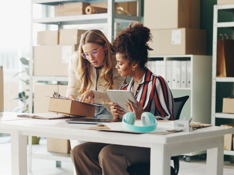 Businesswomen looking at a clipboard and discussing.
