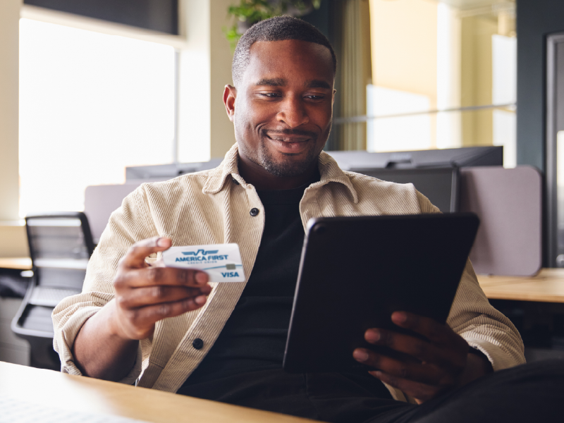 A man holding a tablet and an America First Visa.