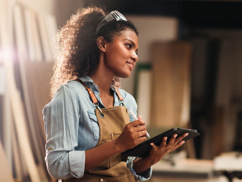 A woman in a woodshop on a tablet.
