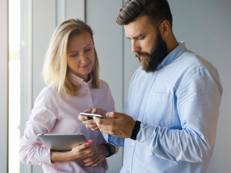 A man and woman reviewing things on a smartphone.