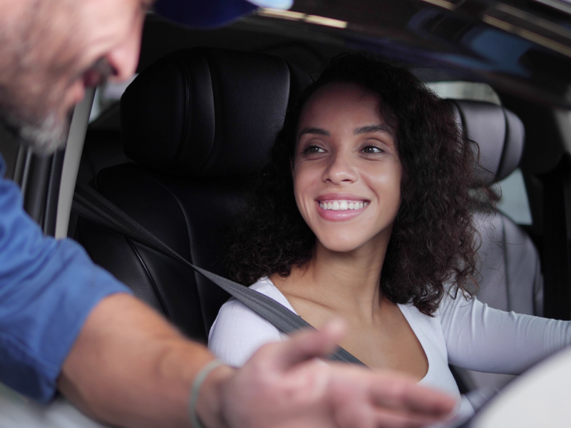 A woman talking to a service professional from inside her car.