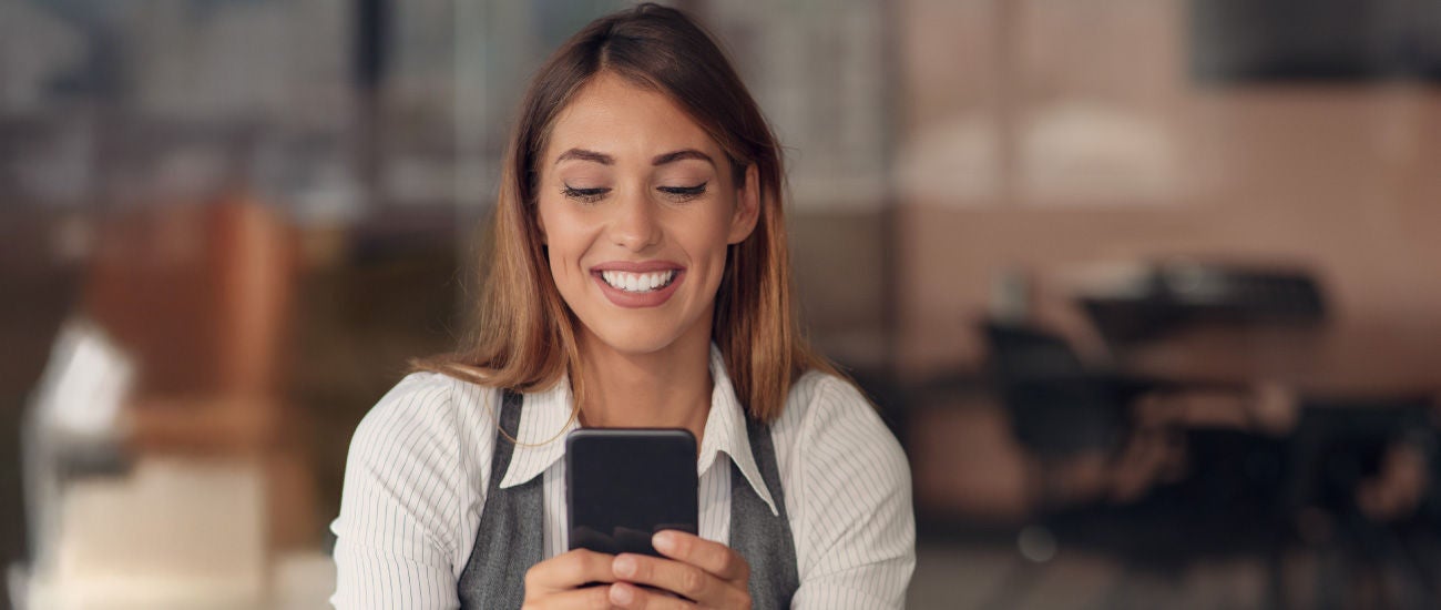 an image of a woman looking at a phone and smiling.