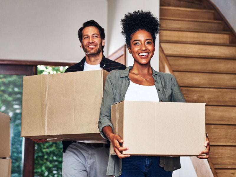 a couple carrying boxes into their new home