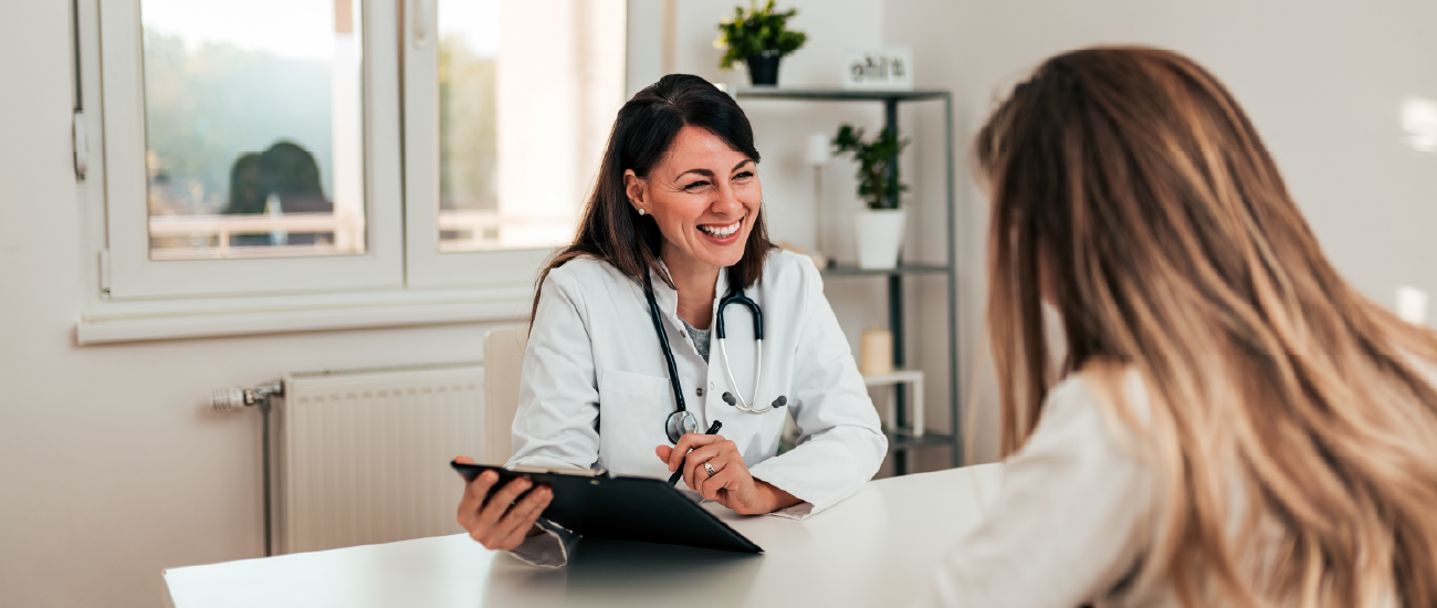an image of a doctor sitting at a desk smiling.