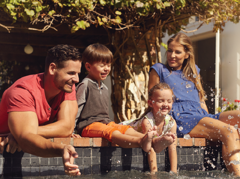 An image of a family sitting near a backyard pool.
