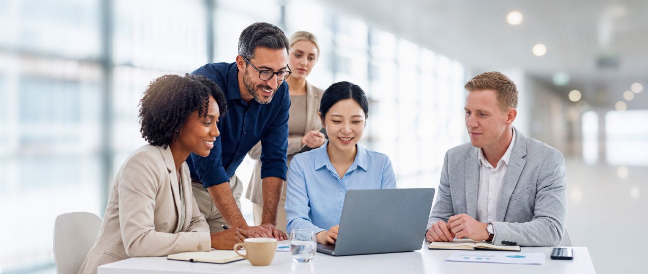 A group of business professionals gathered around a computer.